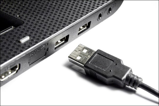 Laptop mit USB-Anschlüssen und USB-Kabel auf weißem Hintergrund