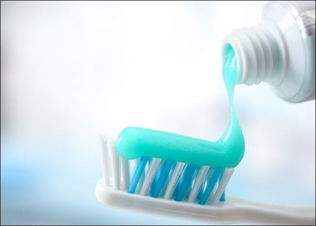 Zahnpasta wird aus einer Tube auf eine Zahnbürste gespritzt.