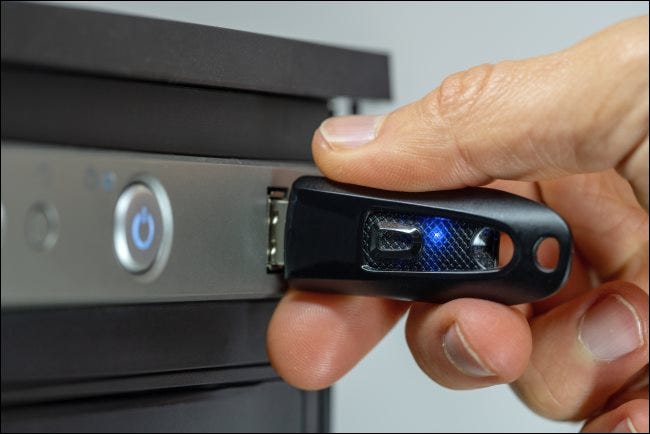 Eine Hand, die ein USB-Laufwerk mit einer LED einsteckt.